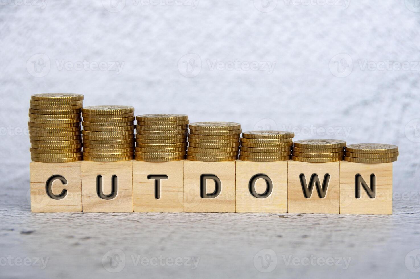 Cutdown text on wooden cubes with stacking golden coins. Business concept photo