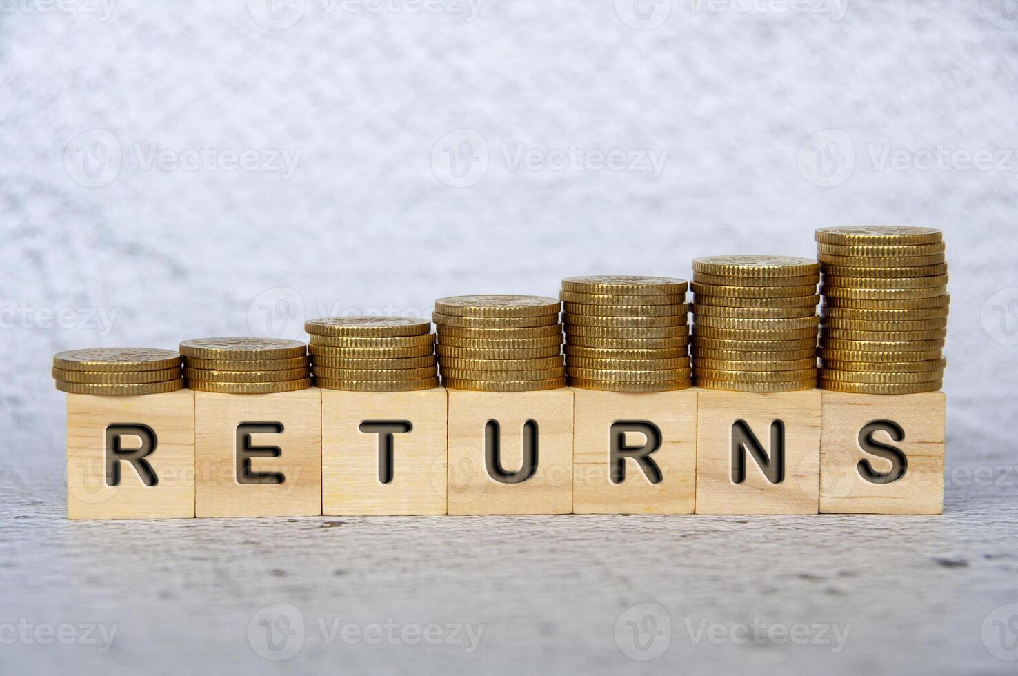 Returns text on wooden cubes with stacking golden coins. Business concept photo