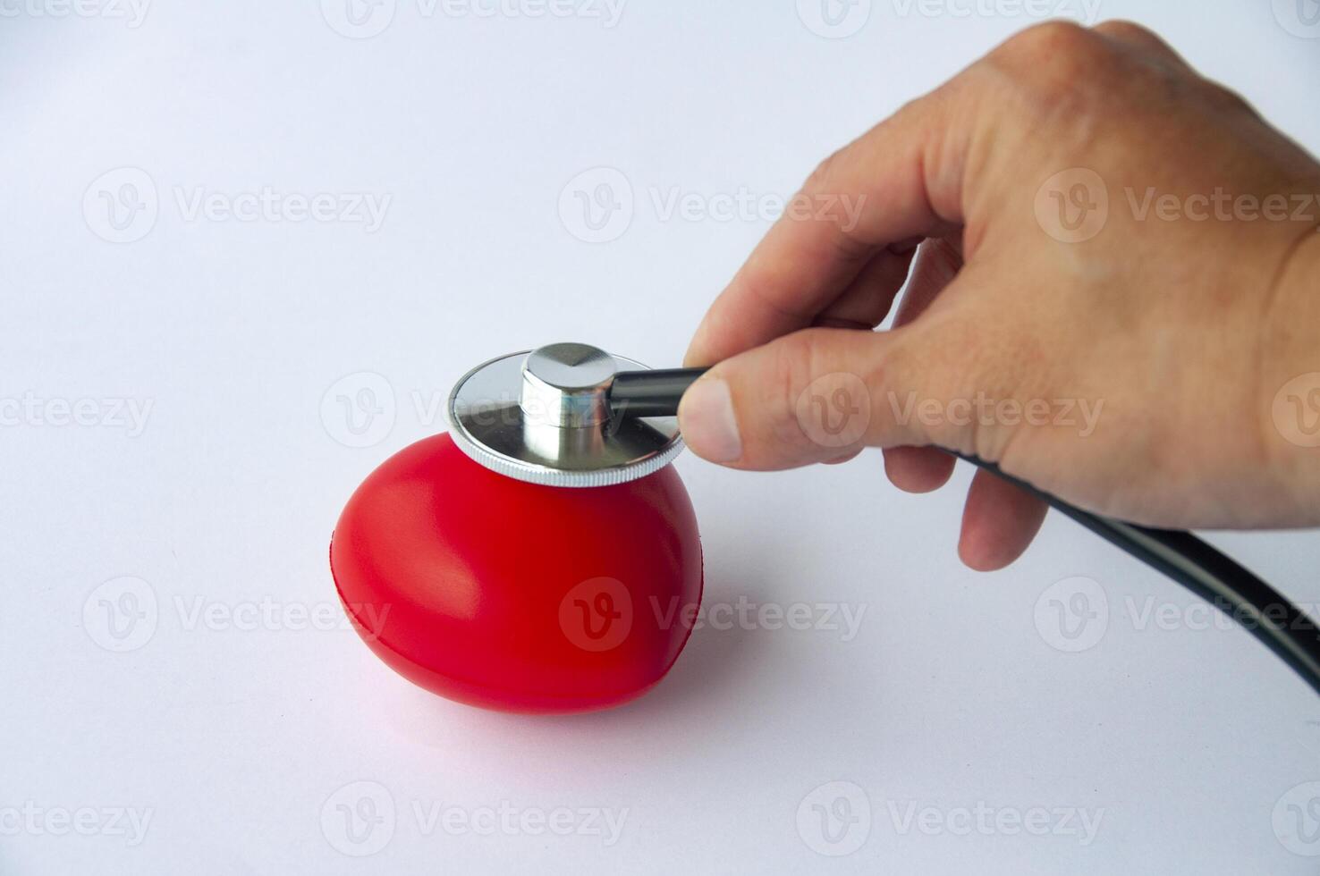 Top view of hand holding stethoscope and a red heart shaped with customizable space for text. Medical and health concept photo