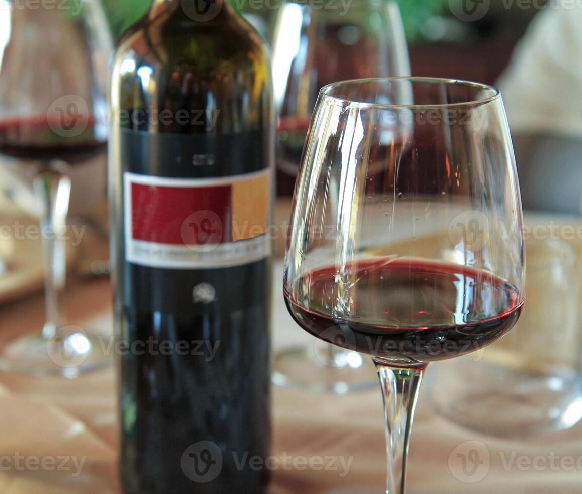 Glass of red wine with bottle on elegant dining table. photo