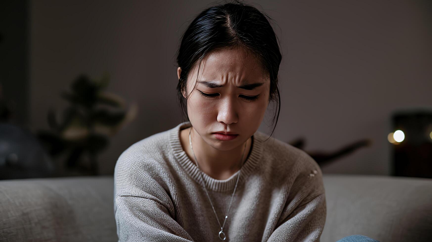 Sad young woman sits alone feeling downcast and lost in soft dim lighting a moment of quiet photo