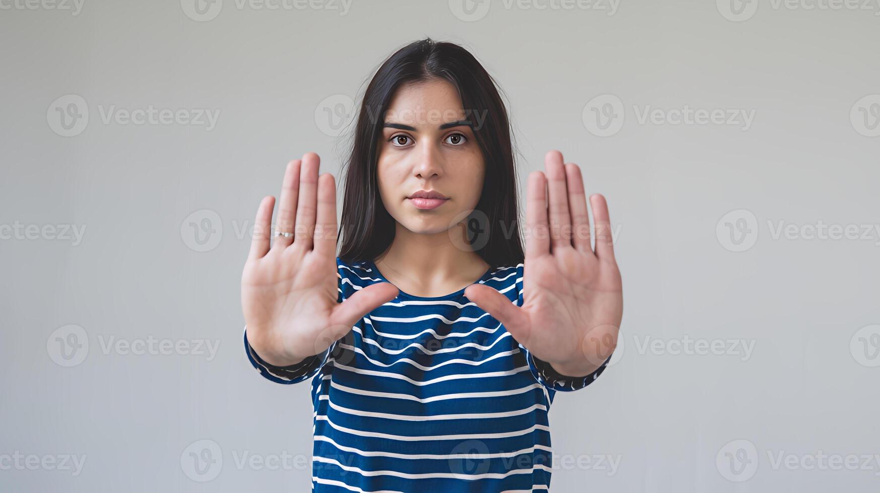 Young woman showing stop hand gesture serious expression neutral background simple studio shot clear photo