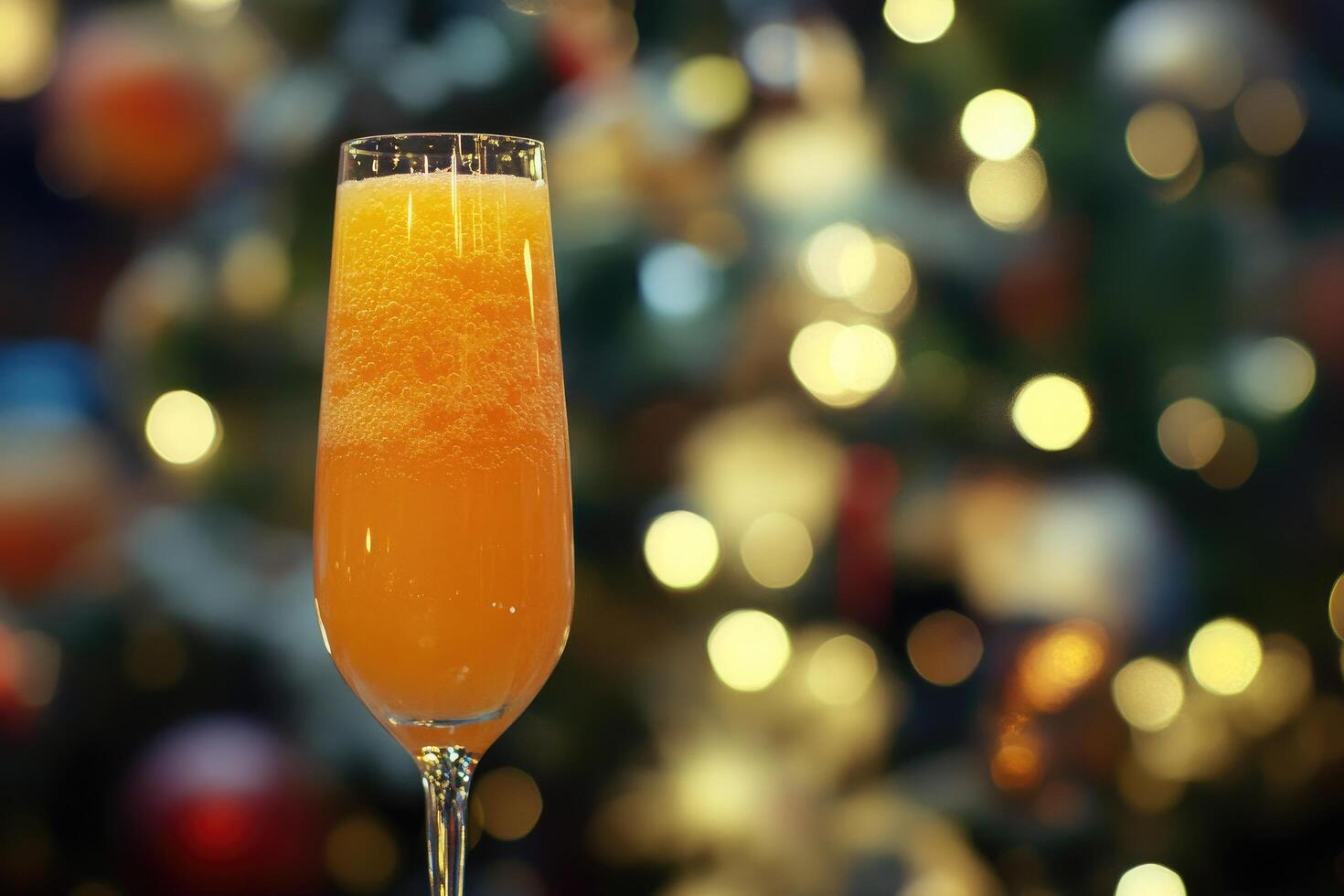 A glass of orange juice with a christmas tree in the background photo