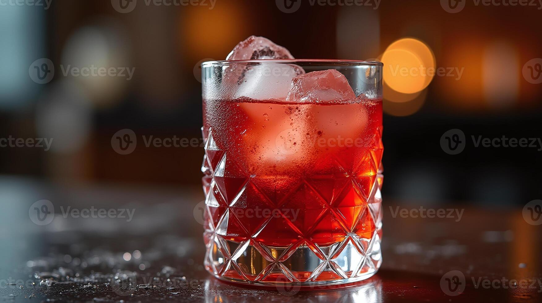 A crystal-clear glass holds a vibrant red beverage with ice cubes, set against a softly blurred background. photo