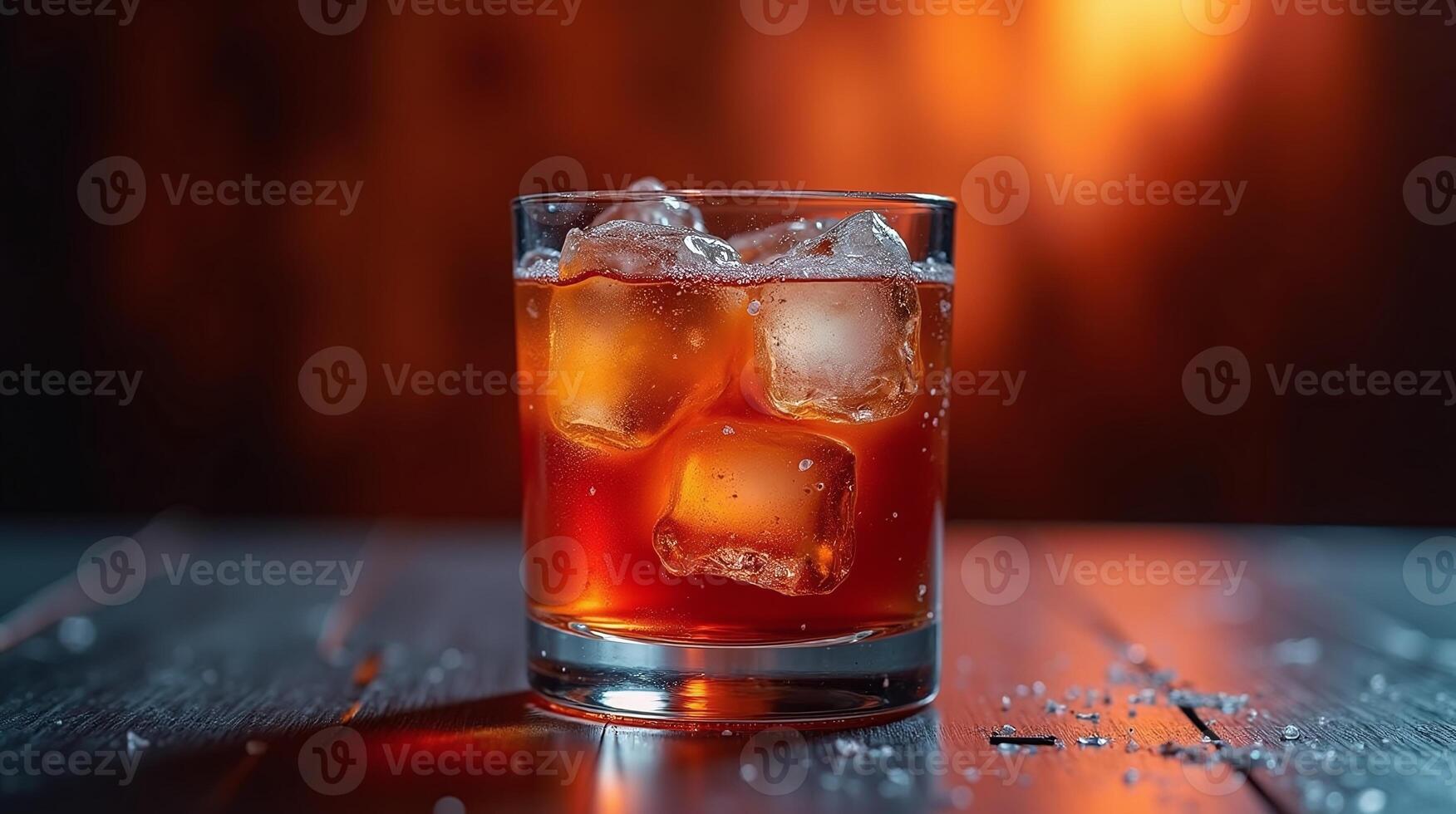 A glass of amber liquid with melting ice cubes. photo