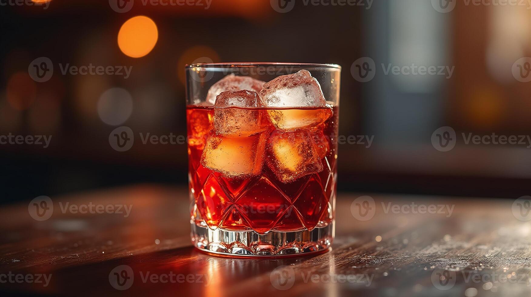 An amber-hued cocktail with ice in a cut-glass tumbler. photo
