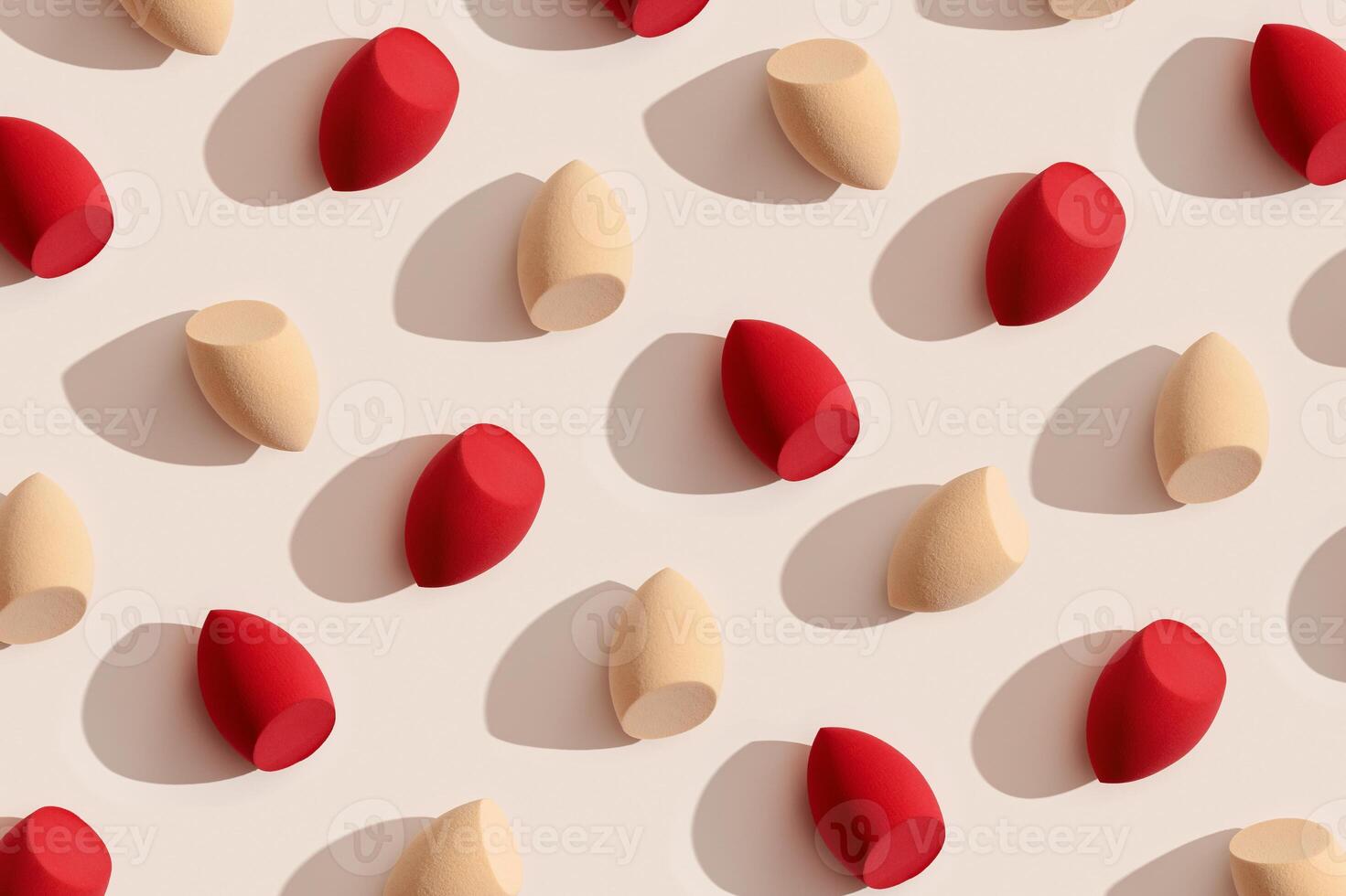 Trend pattern from makeup sponges beige and red colored for foundation cream on beige color background with shadows from sunlight. Geometric flat lay beauty blender, cosmetic sponge, make up puff photo