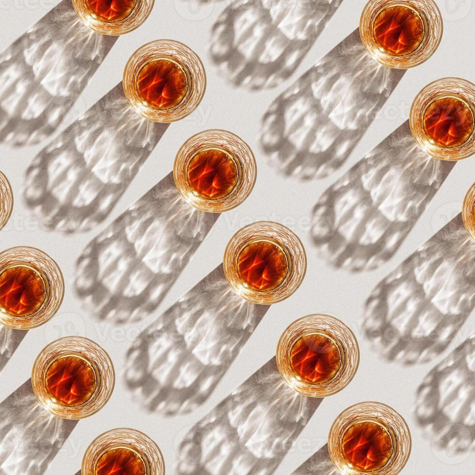 Whiskey Glasses with Shadows and sunlight Reflection on beige, glass strong alcohol, top view repeated pattern, aesthetic top view summer still life, refraction at crystal shine cups, caustics photo