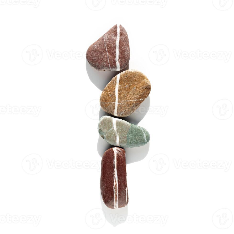 Creative arrangement of natural color stones. Smooth pebbles in row isolated on white background. Minimal trend summer flat lay, top view still life with bright sea pebble on the same line photo