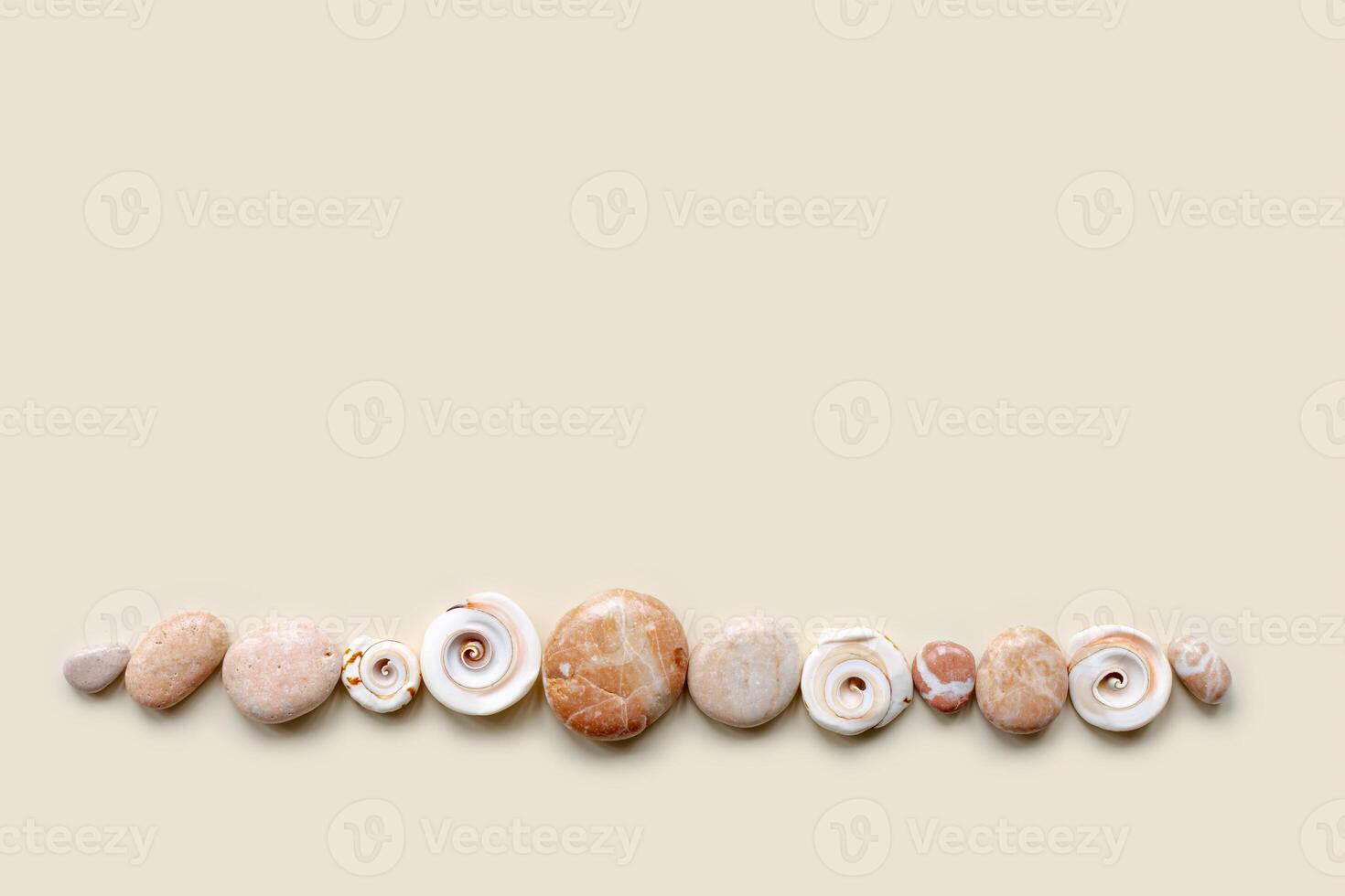 Top view close up colored pebbles sea stones and shells on sand color background. Row from natural round smooth stone neutral tones. Minimal style banner, summer concept, empty space photo