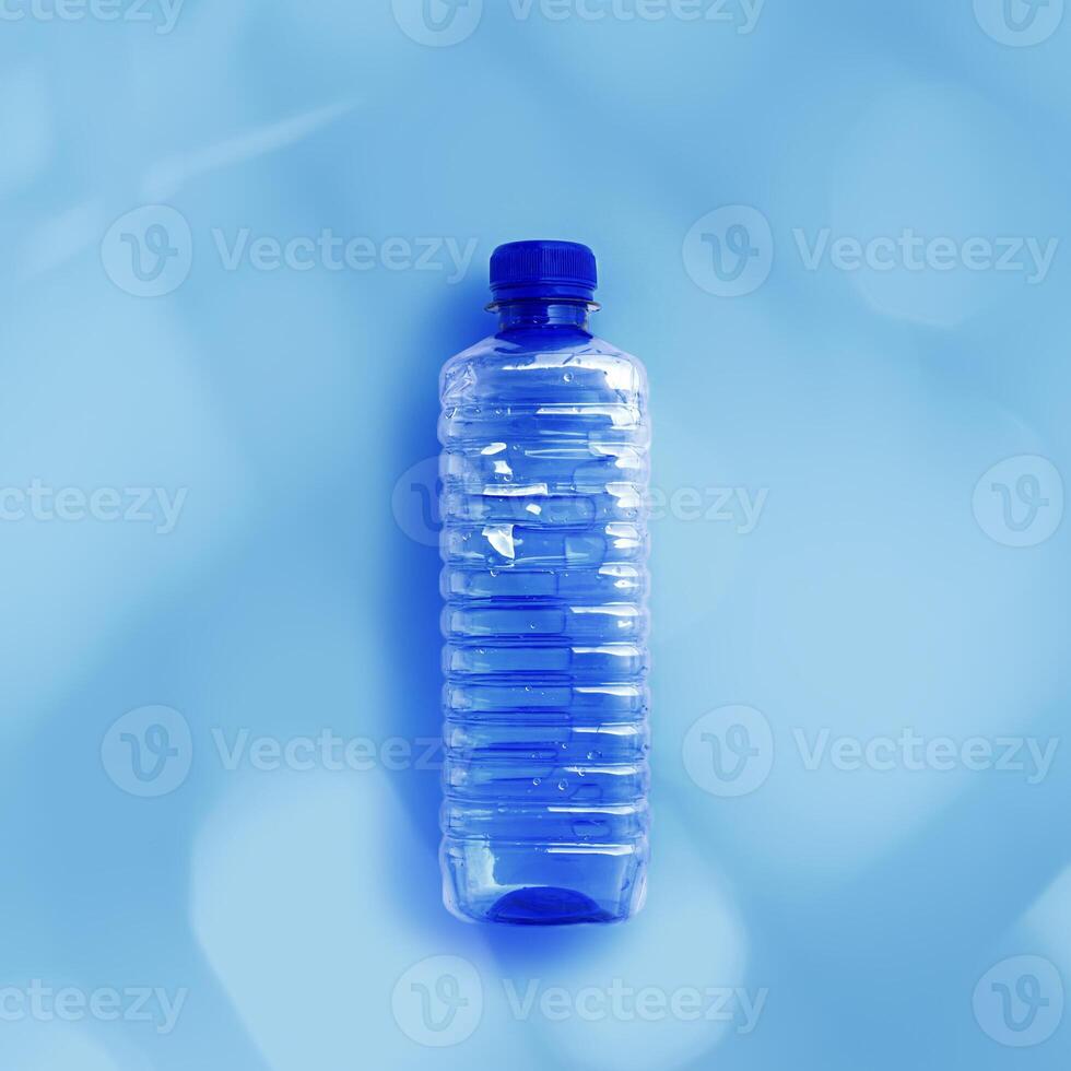 Clear plastic water bottle for water half litre on light blue background closeup, minimal style object, aesthetic top view, Pollution, environmental protection. Eco trend to reduce disposable plastics photo