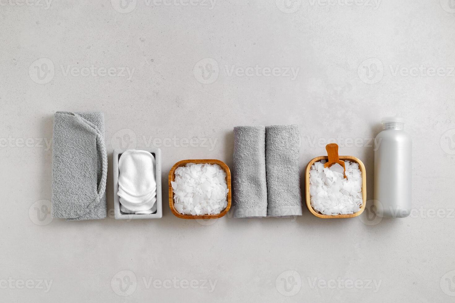 Spa wellness, bath products as minimal style aesthetic pattern, magnesium salt flakes, folded grey towels, natural brushes, massagers, reusable pads, gray background, top view lifestyle content photo