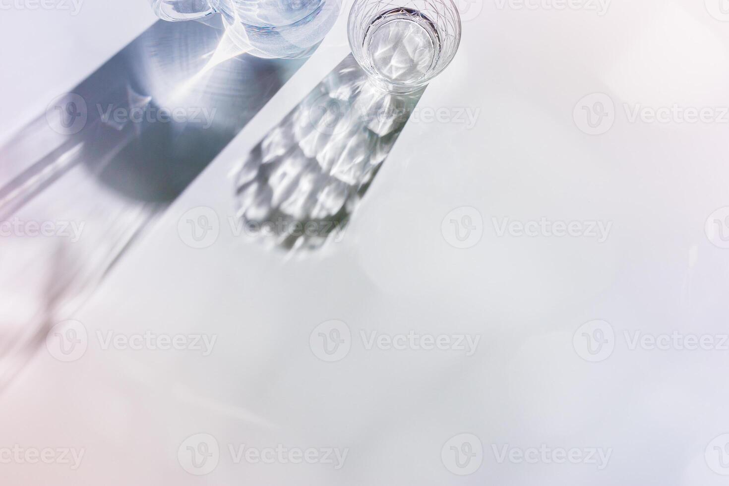 Water Glass with shadows at sunlight on white, delicate blue pink color, minimal aesthetic top view shiny glasses at natural light, summer drink concept, pastel gradient interplay light and shadow photo
