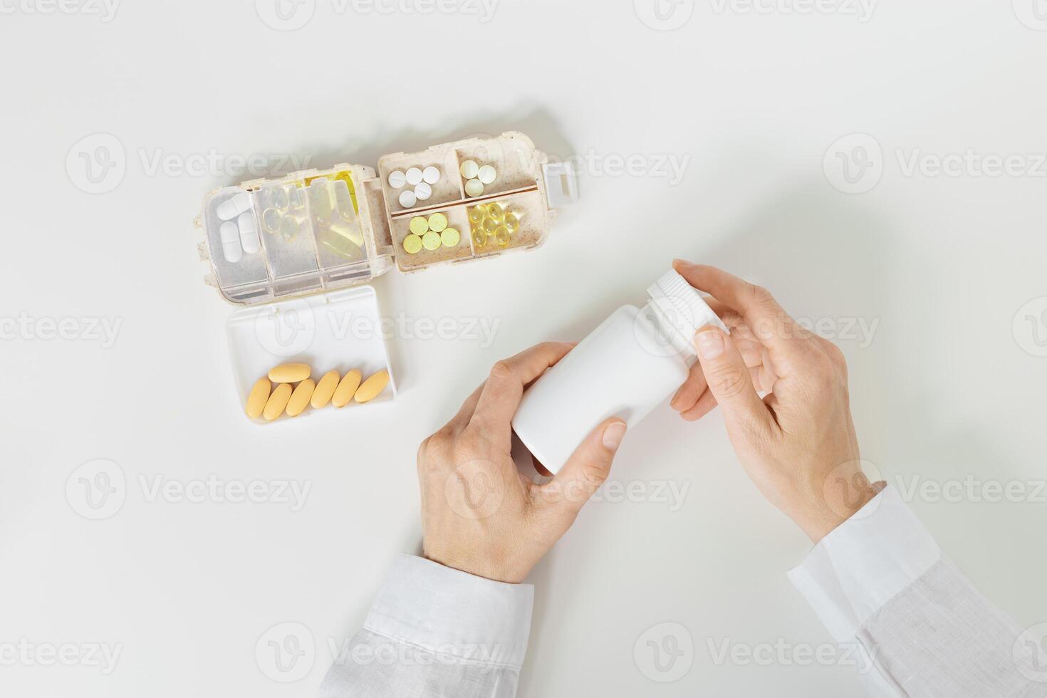 Pill box daily taking medicine, with tablets and capsules. Drugs, medication as alternative medicine for treatment and good health. female hands holding medicine dose box with pills on table, photo