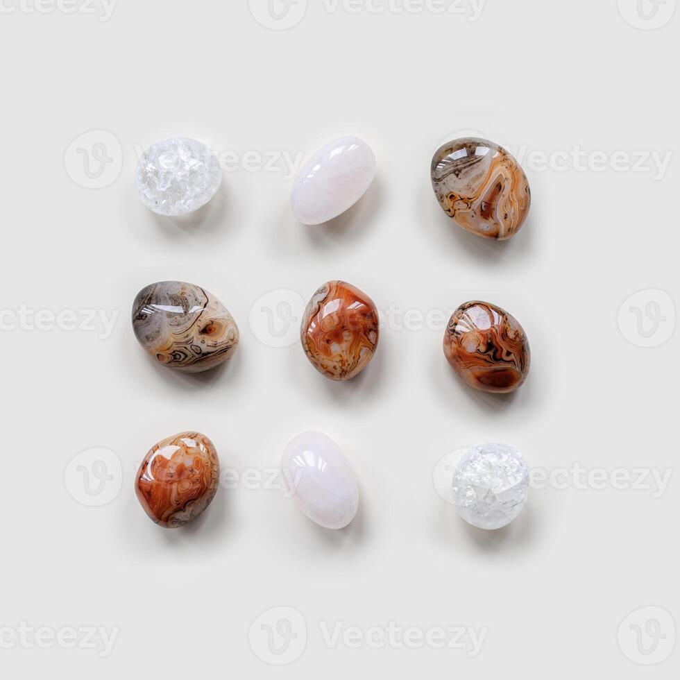 Creative arrangement of natural colored stones. Smooth round pebbles as square pattern on light white background. Minimal summer flat lay, top view composition with different gemstones photo