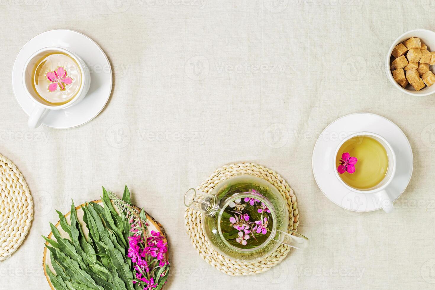 Herbal tea from kipreya leaves in white cups on linen fabric table background, fireweed green leaves and flowers on wooden tray. Flavored herbal tea from wild plants, healing hot beverage. photo