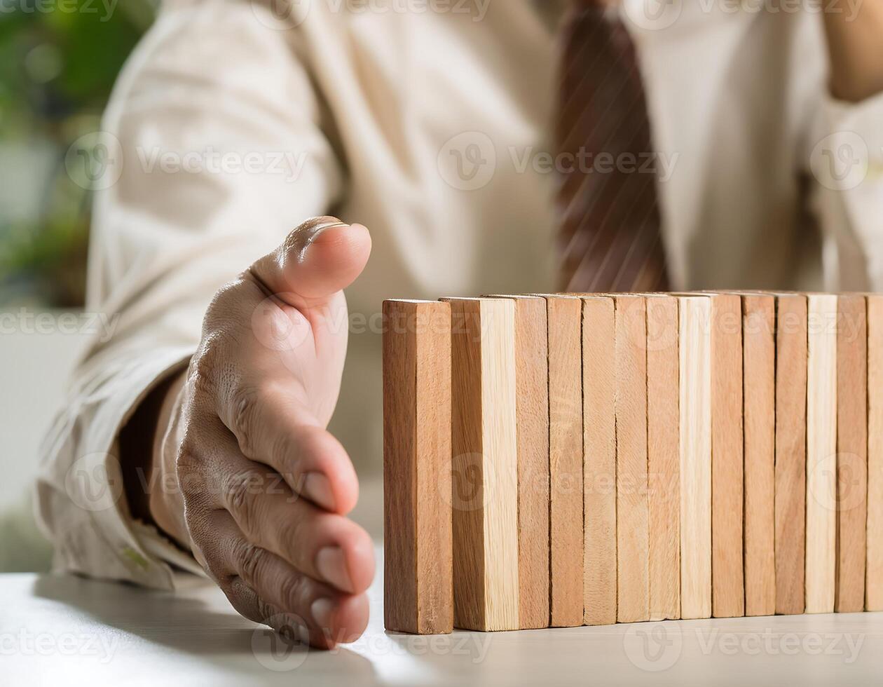 Hand Blocking Domino Effect to Save House Model photo