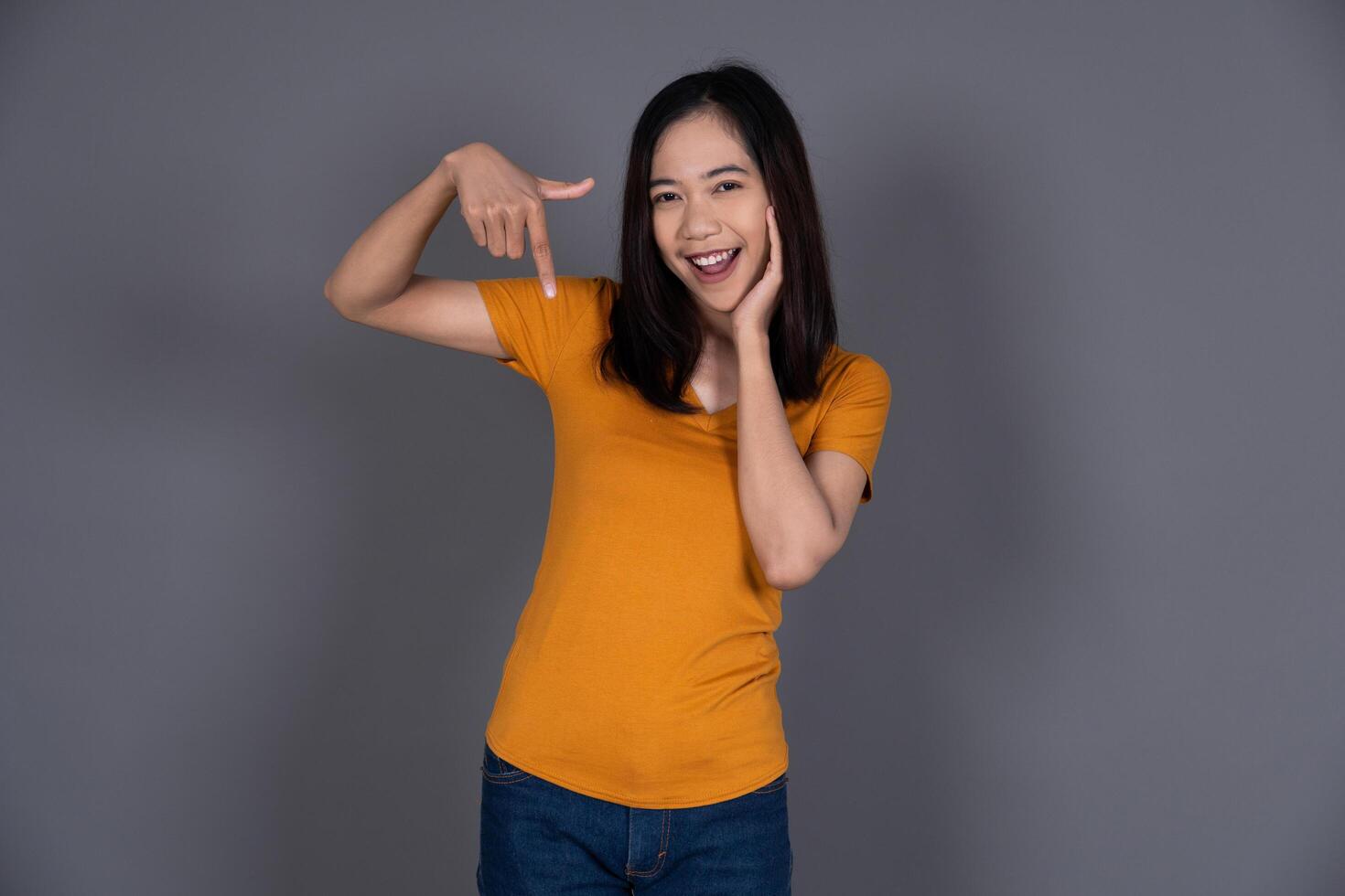 Smiling Portrait of a Young Female Pointing Down with Joyful Expression photo
