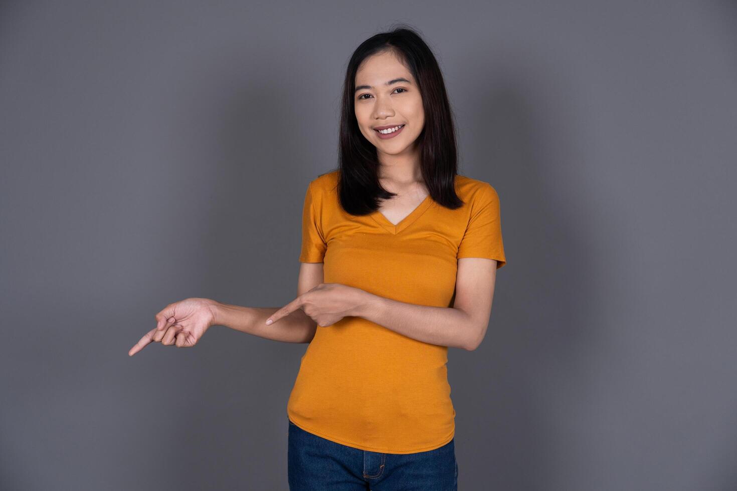 Smiling Portrait of a Young Girl Pointing Down with Joyful Expression photo