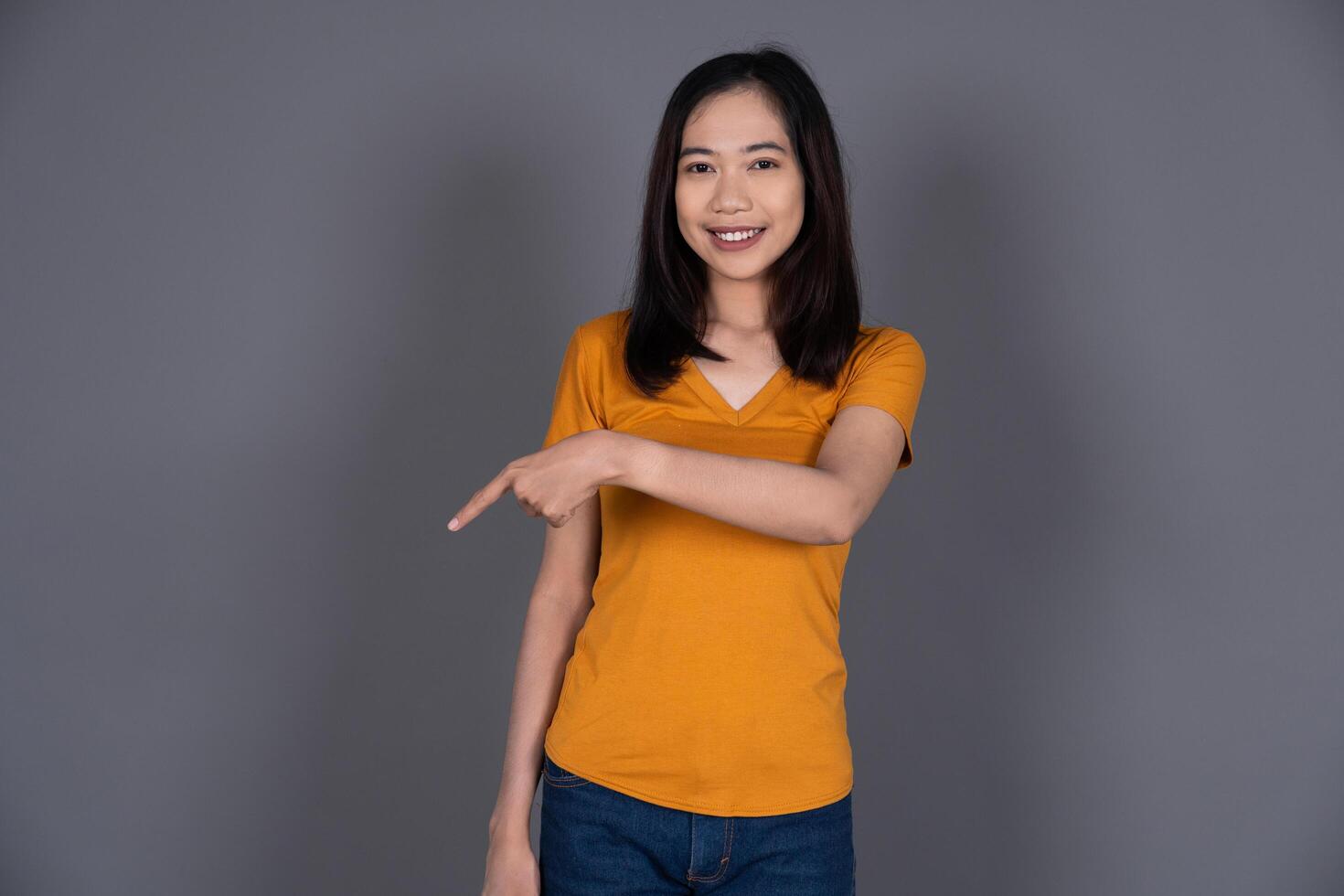 Smiling Portrait of a Young Girl Pointing Down with Joyful Expression Isolated photo
