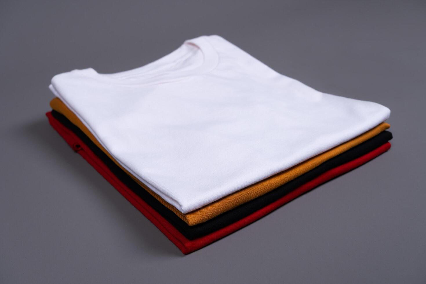 A stack of folded t-shirts against a grey background photo