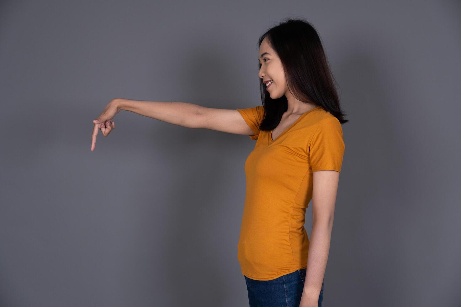 Smiling Portrait of a Young Girl Pointing Down with Joyful Expression Isolated Background photo