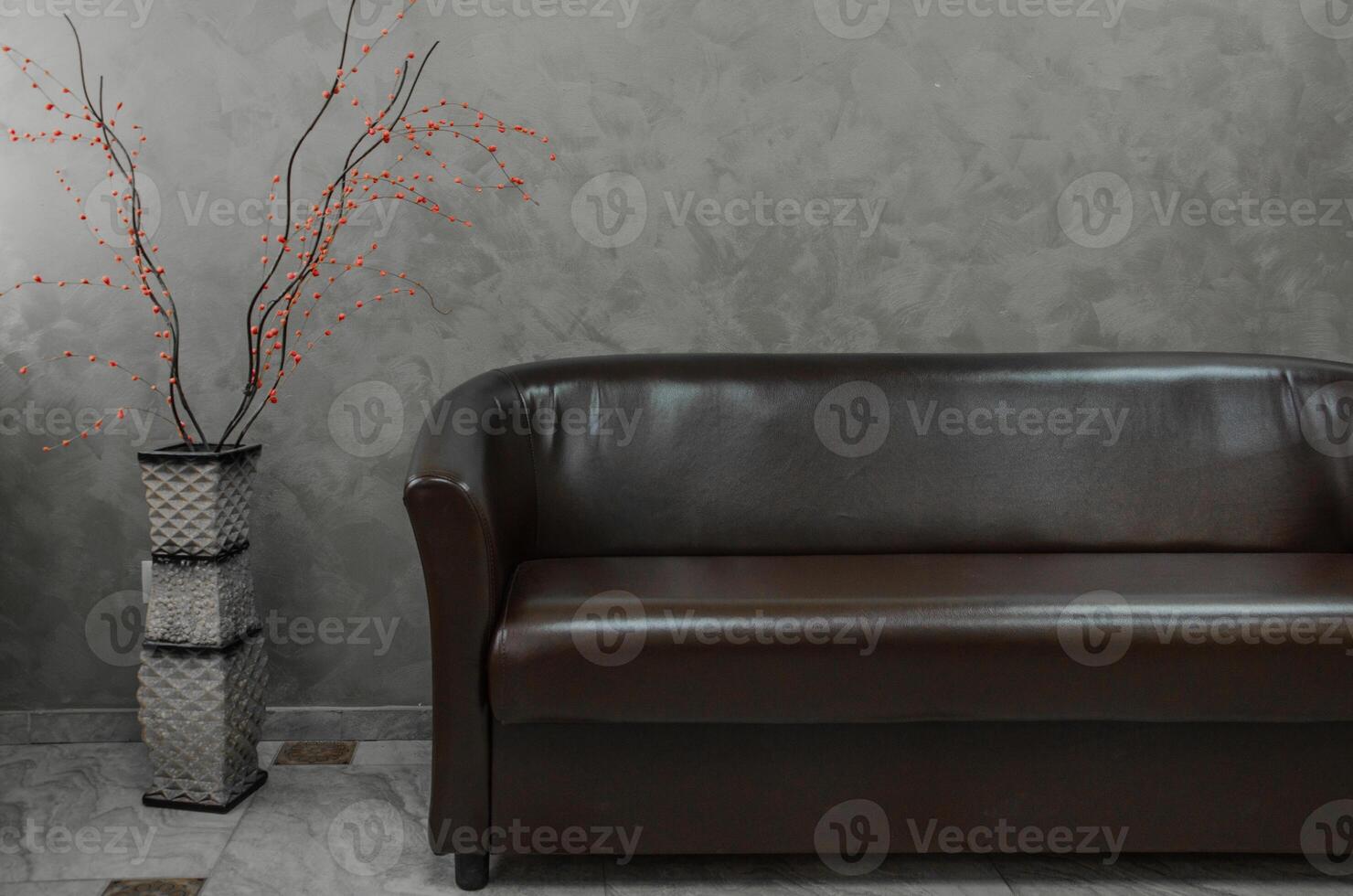 Beautiful artificial flowers in a vase near the sofa in the interior and design of the room. High quality photo