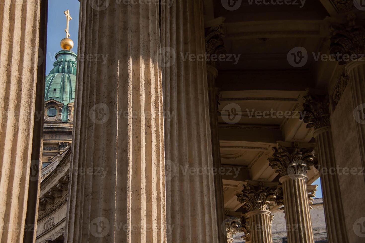 Architecture Kazan Cathedral St. Petersburg. Sunlight highlights intricate details of Grand Architectural Columns foreground, leading eye to historic dome topped with cross and golden orb background photo