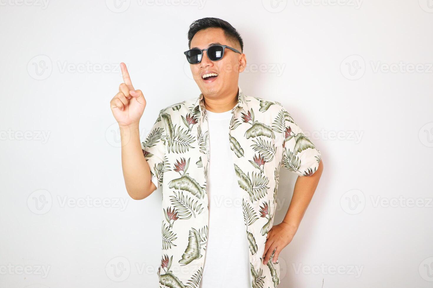 Asian man wearing a white beach shirt showing enthusiastic expression with right hand pointing up photo