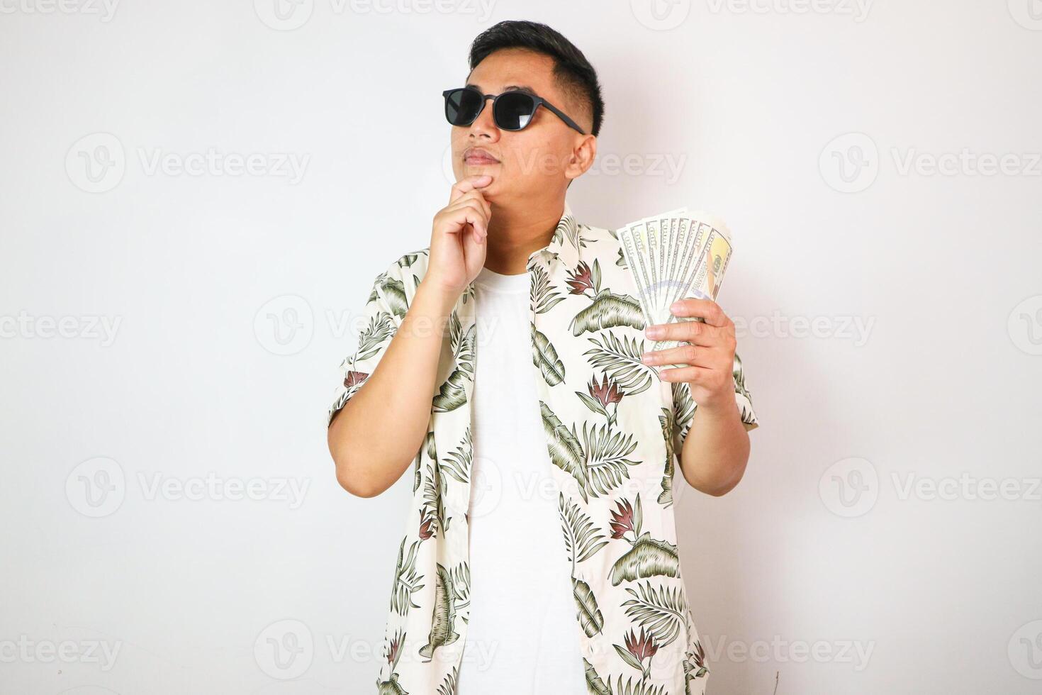 Asian man showing thinking expression when looking to US dollar money that he hold photo