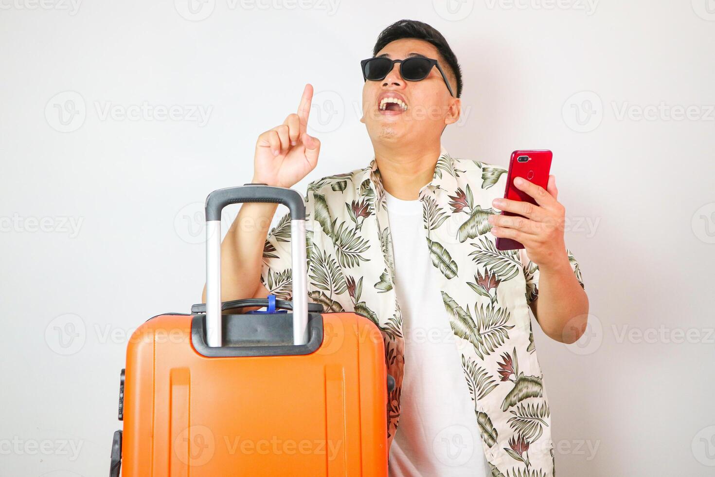 Young man smiling and pointing fingers up standing against white background, travel time concept, copy space. photo