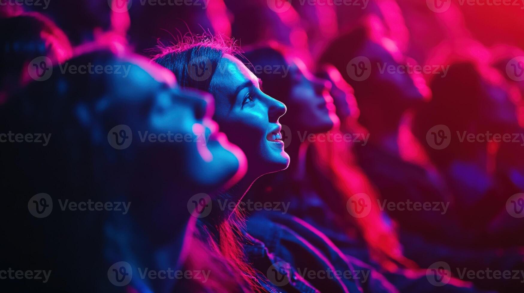 Intimate shot of audience members in close proximity illuminated by colorful stage lights. Faces are alive with emotionlaughter excitement and anticipationas the pulsating rhythm o photo