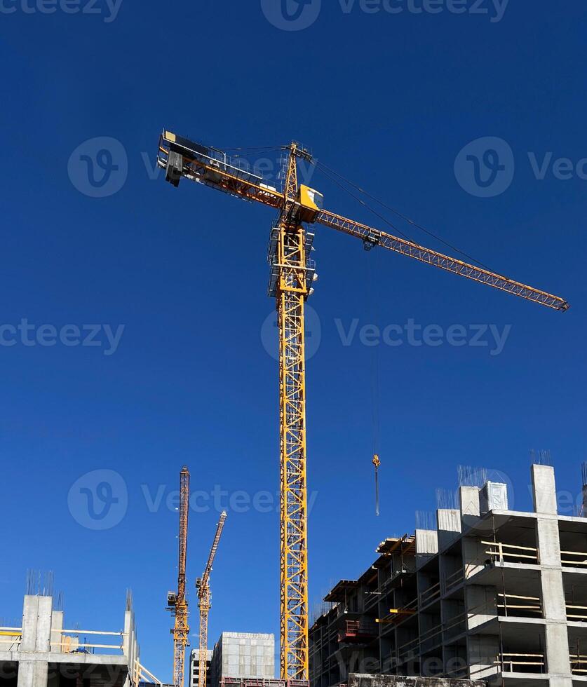 Tower cranes in action on a construction site. High-rise buildings under development showcase crane operations for lifting materials against blue sky , industrial scene photo