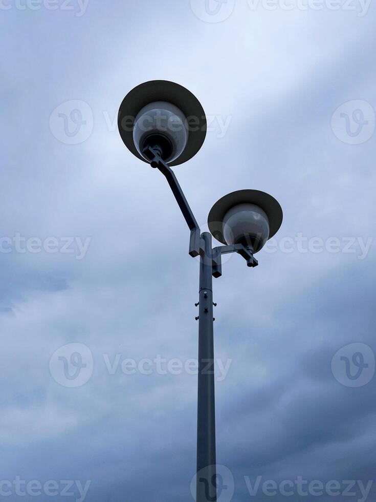 minimalist photo of modern street lamp with two globe-shaped lights, set against an overcast sky, emphasizes the simplicity and functionality of urban design