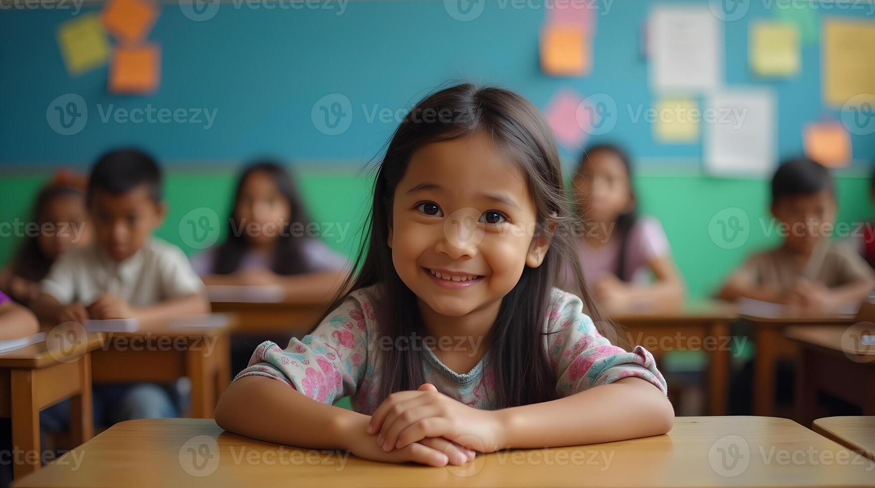 A young girl smiles at the camera while sitting at a desk photo