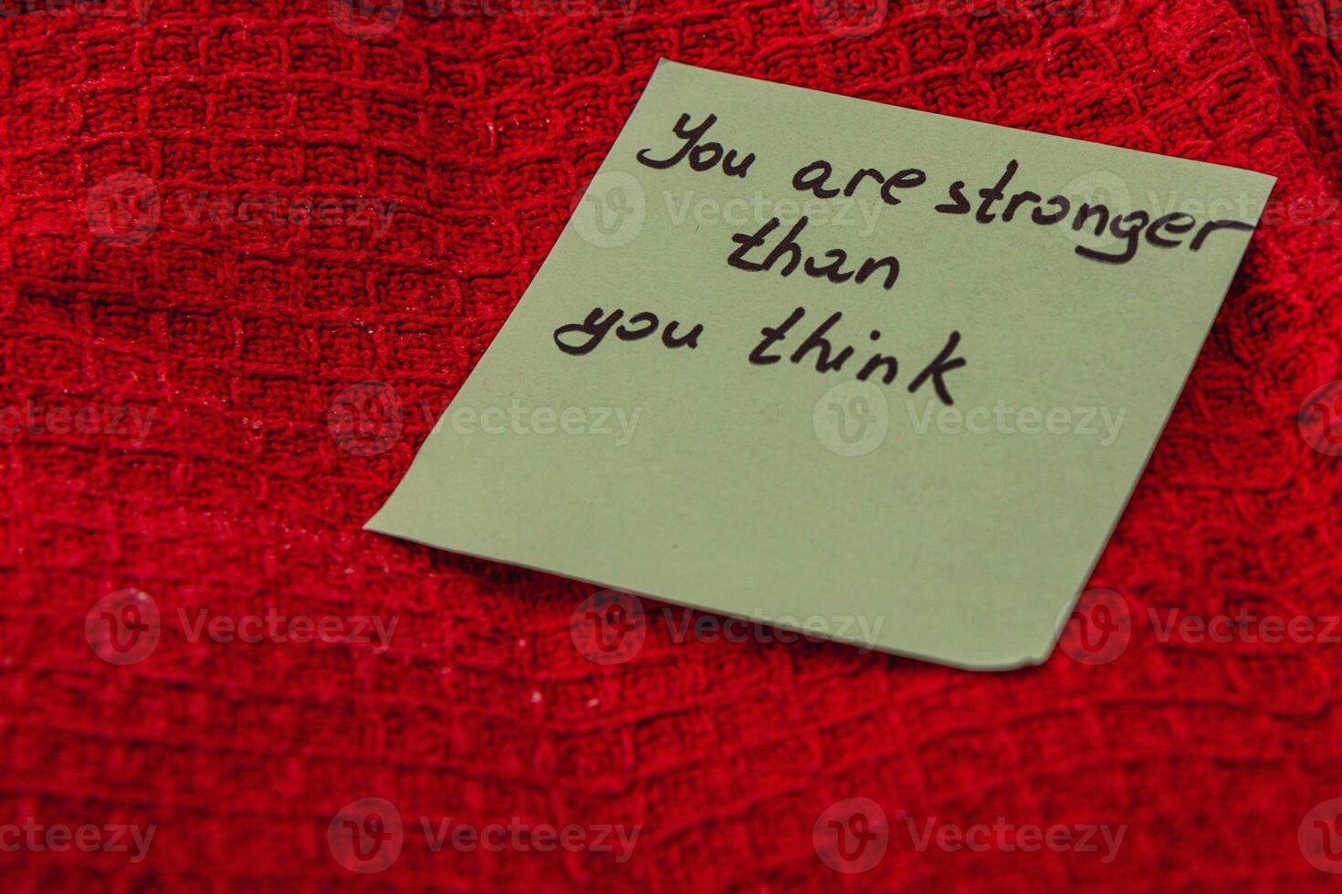 Message of encouragement on a note placed on a red textured surface photo