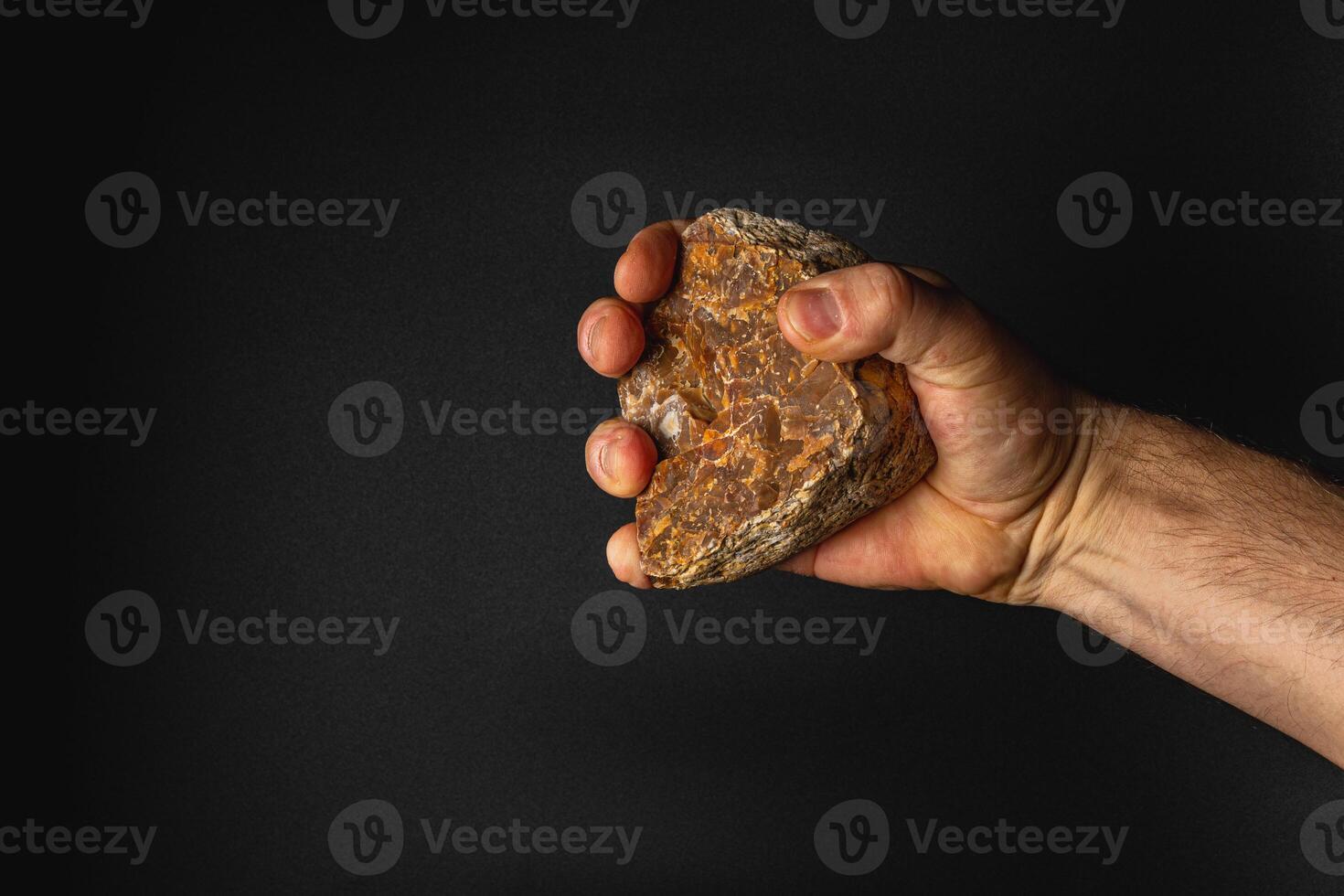 Hand holding a rock against a dark background photo