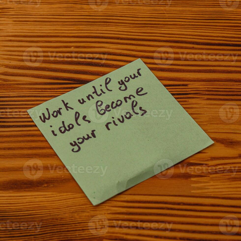 Inspirational reminder on a sticky note placed on a wooden table photo