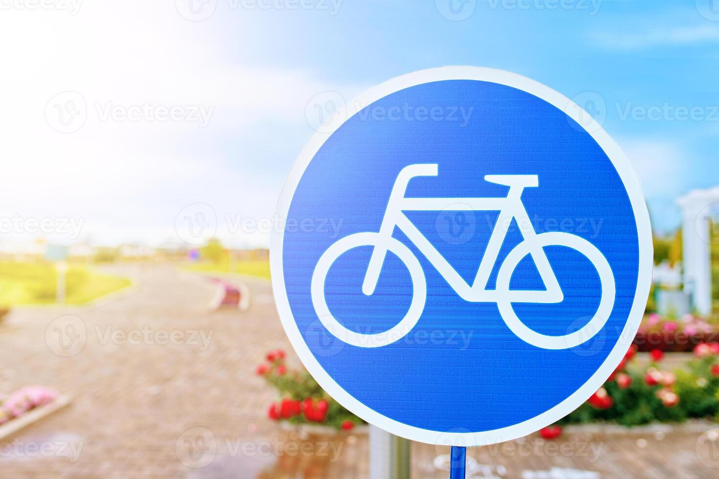A vibrant blue and white sign showcasing a bicycle wheel against the azure sky and fluffy clouds, symbolizing nature and freedom. The design includes bicycle handlebars and frame details photo