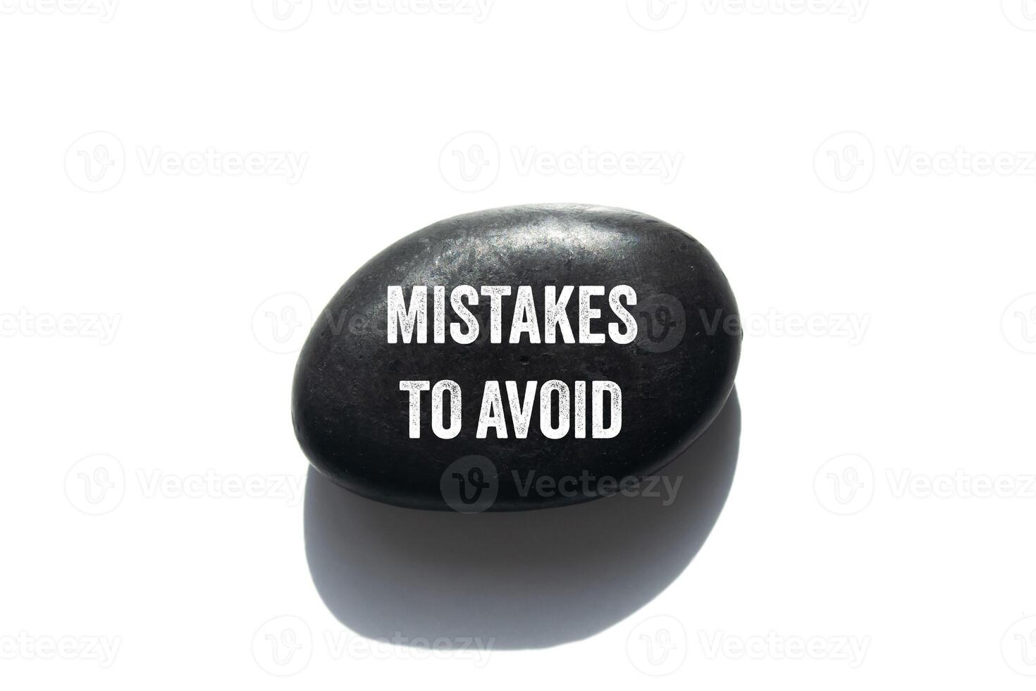 Mistakes to avoid message written on black stone on white background. Conceptual mistakes to avoid symbol. Copy space. photo