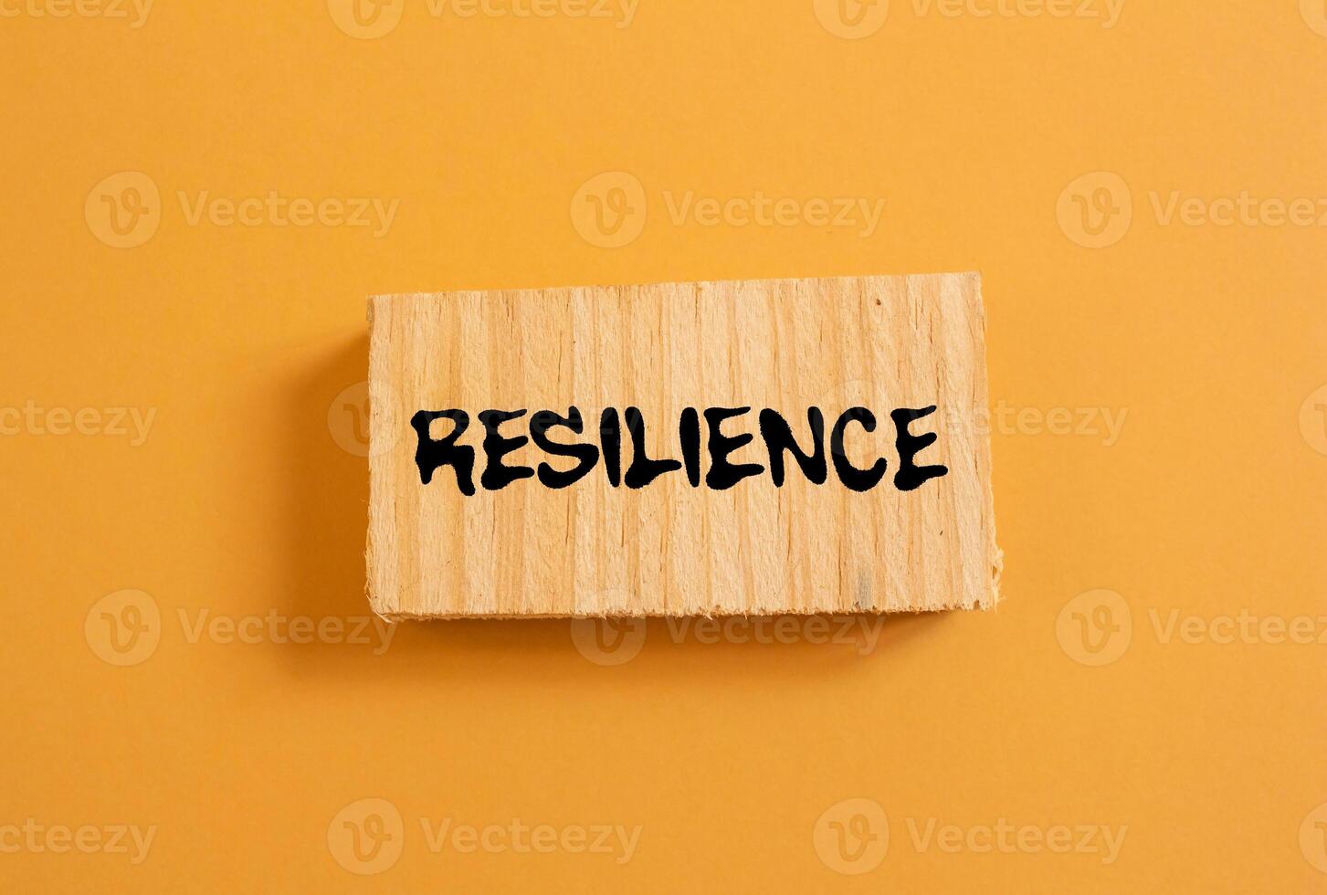 Resilience message written on wood piece on orange background. Conceptual resilience symbol. Copy space. photo