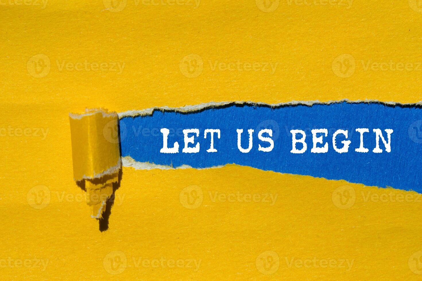 Let us begin message written on ripped torn yellow paper on blue background. Conceptual let us begin symbol. Copy space. photo