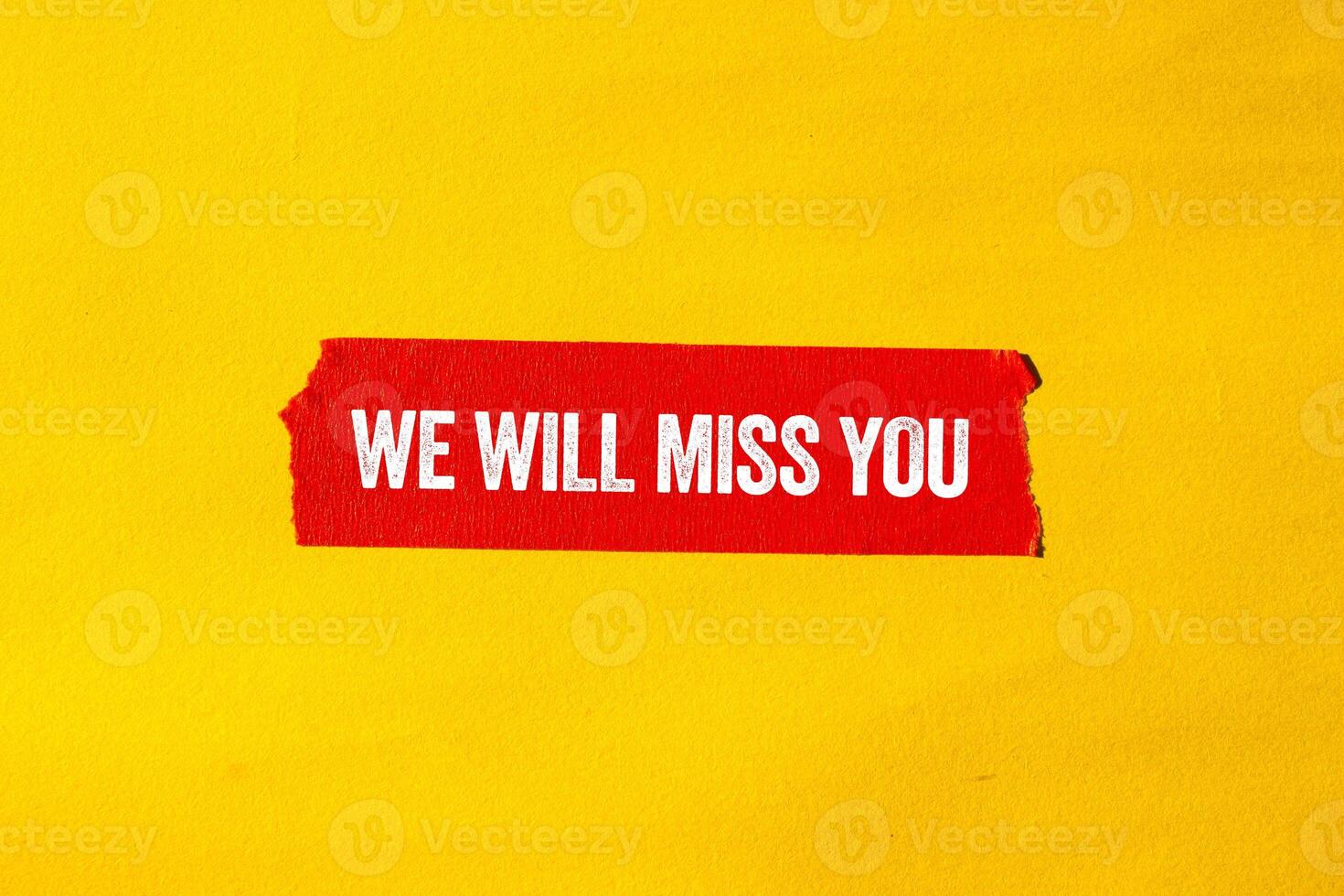We will miss you message written on ripped torn red paper tape on yellow background. Conceptual we will miss you symbol. Copy space. photo