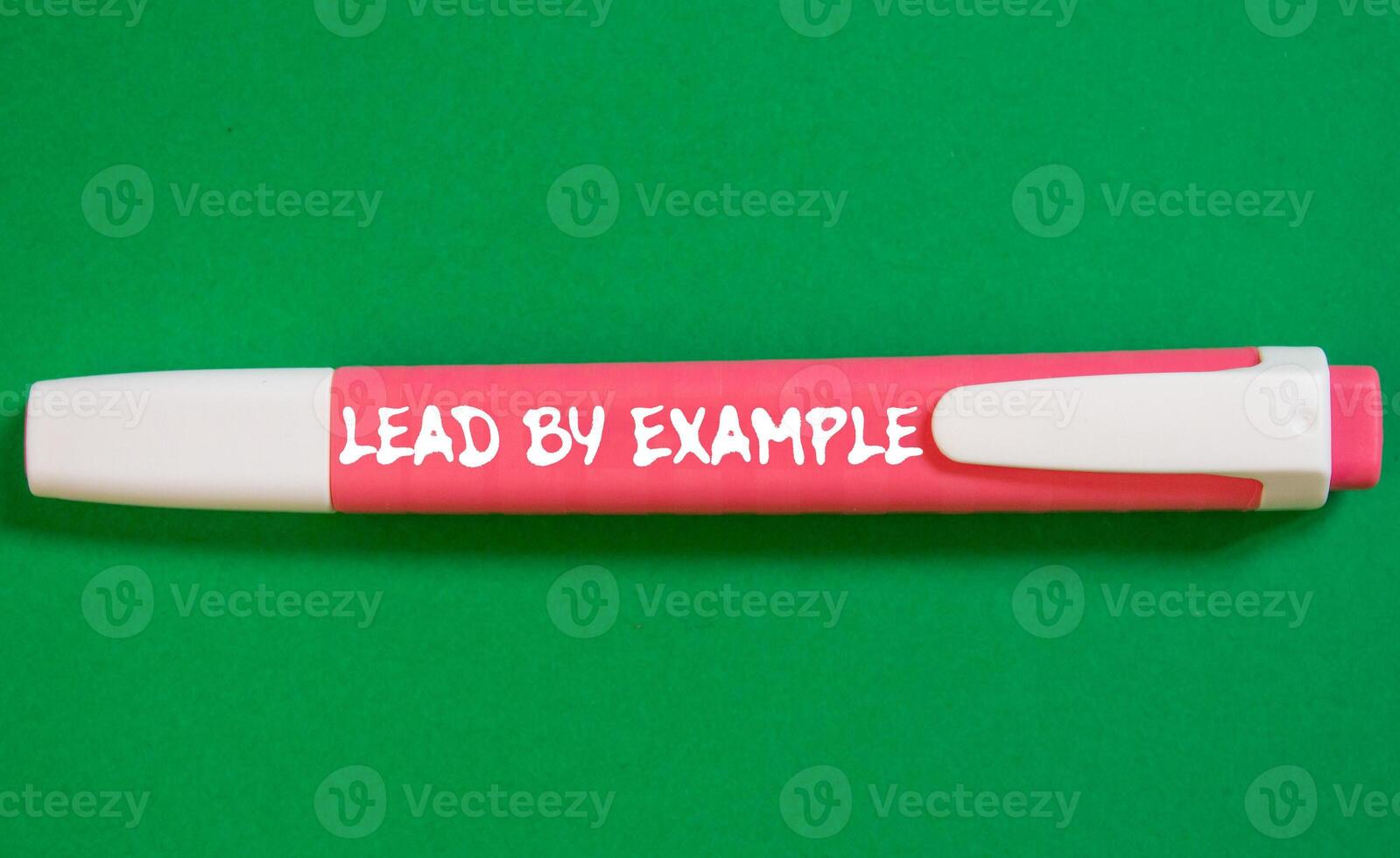 Lead by example message written on pink marker pen on green background. Conceptual lead by example symbol. Copy space. photo