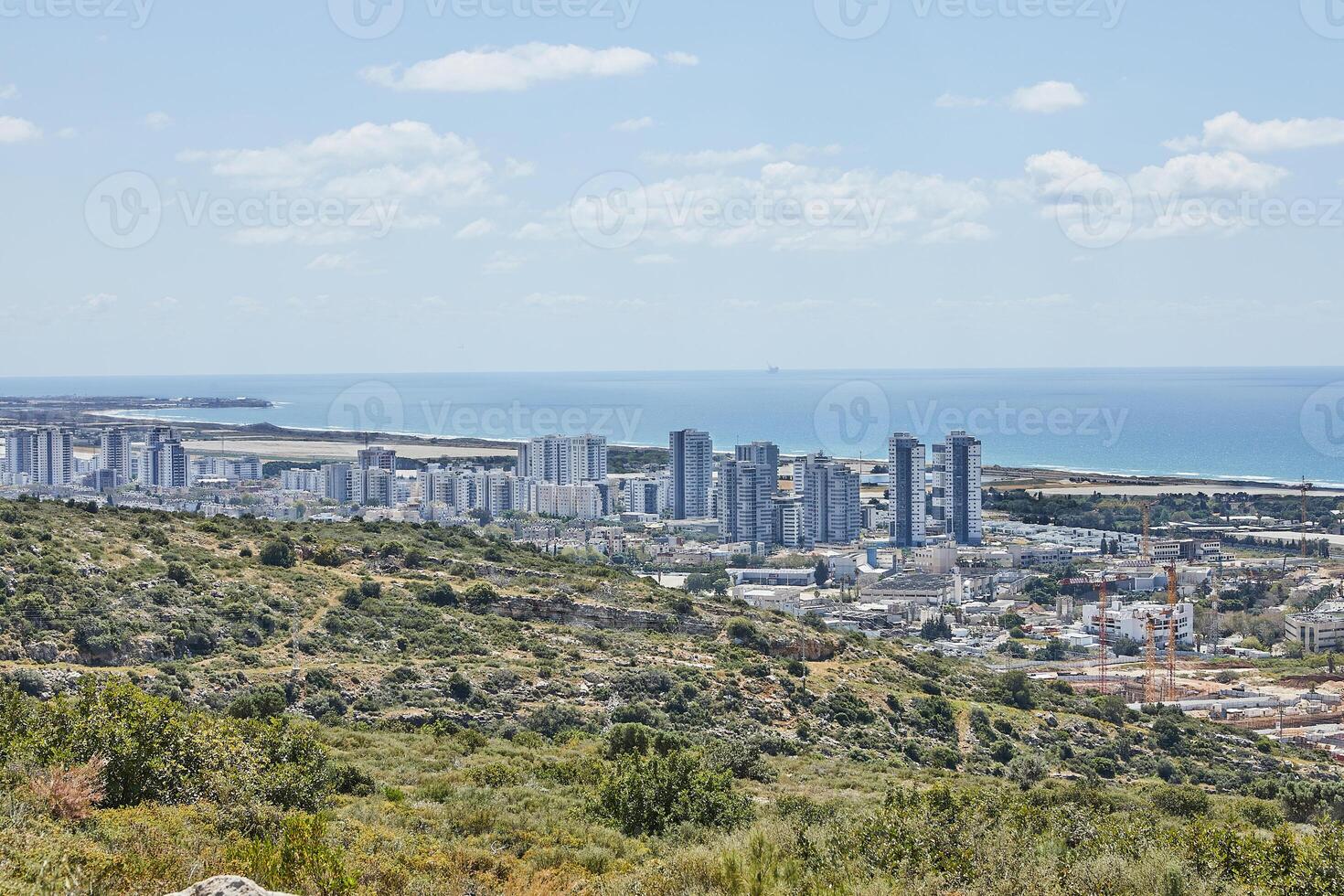 Panoramic view of a coastal city with high-rise apartments, lush green hills, and the sparkling Mediterranean Sea in sunlight photo