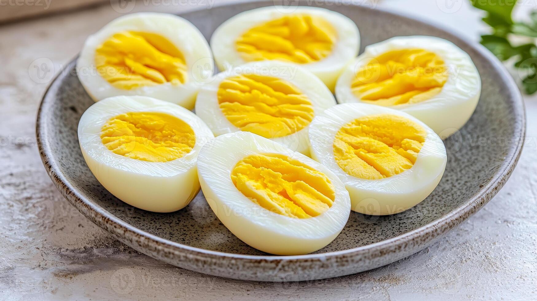 A plate of halved boiled eggs showcasing bright yellow yolks and smooth white egg whites, garnished with parsley on a light background. photo