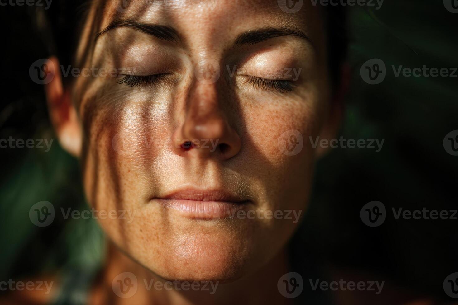 Sunlight casts intricate patterns on a serene face with closed eyes, revealing freckles and a peaceful expression, highlighting natural beauty and tranquility in a close-up portrait photo