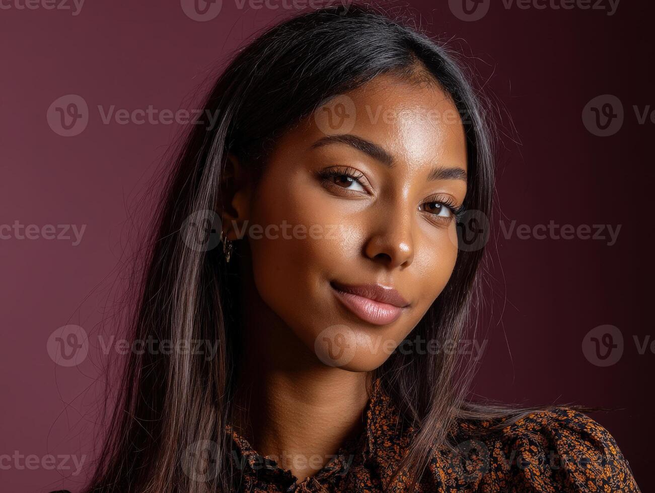 Smiling individual with long dark hair and glowing skin, wearing a patterned outfit and small earrings, confidently posing against a neutral background, exuding charm and poise photo