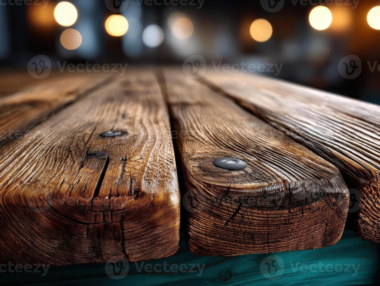 Weathered wooden surface with visible grains and metal nails, set against blurred warm lights in the background creating a cozy atmosphere. No text is present in the image photo