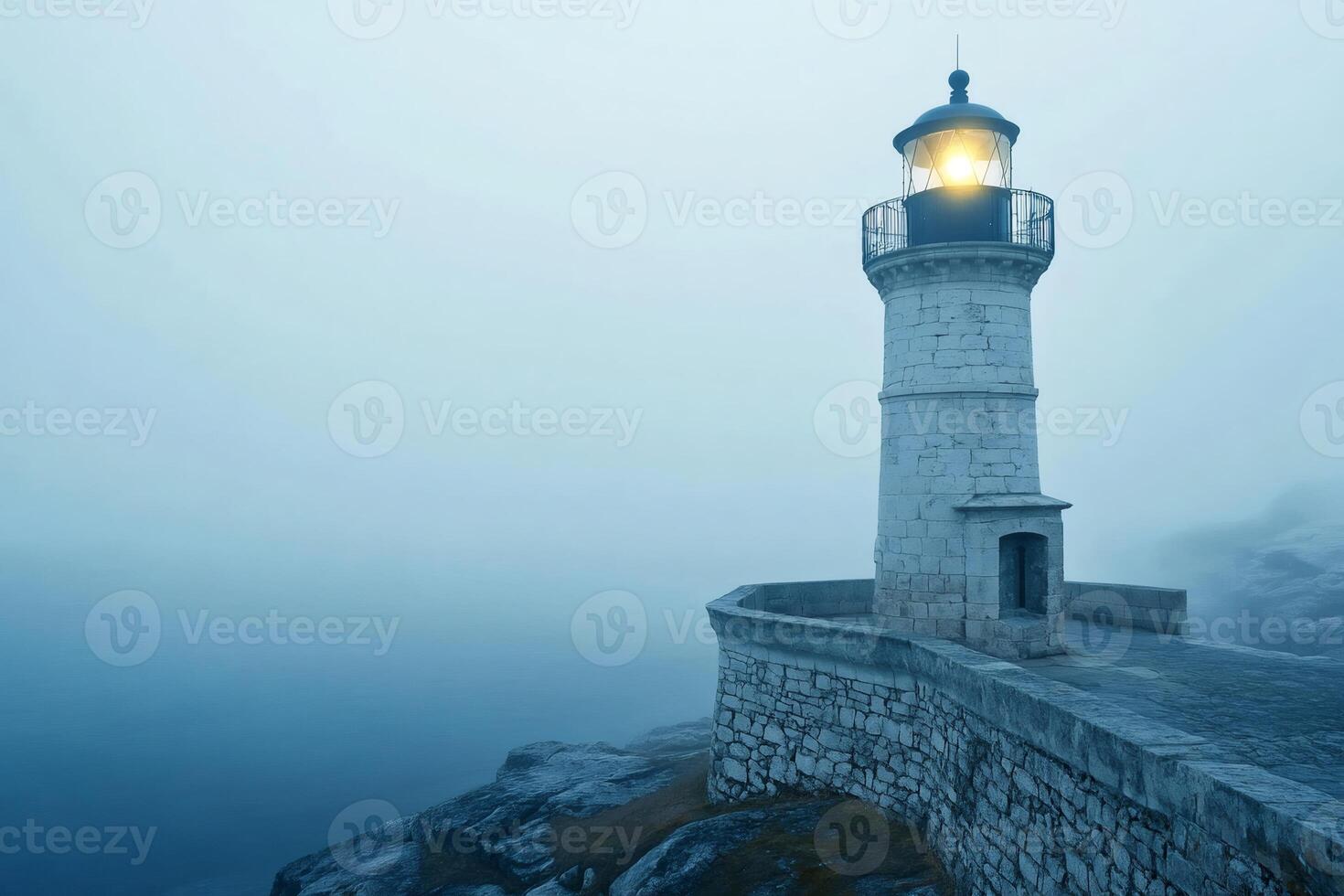 Lighthouse illuminating foggy seascape at twilight photo